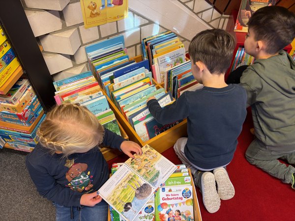 3 Kinder suchen in einer Bücherkiste