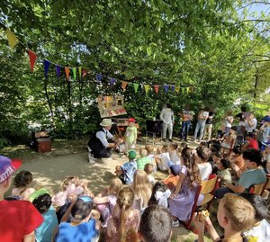 Kinder sitzen im Grünen und schauen einem Zauberer zu