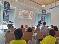 Kinder lauschen im Sitzungsraum einem Vortrag