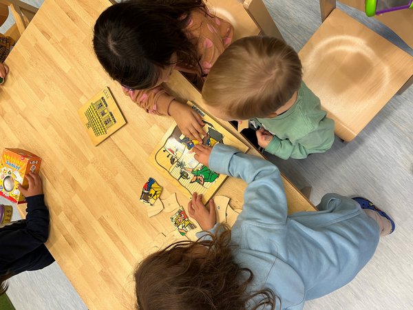 Blick von oben auf 3 Kinder, die puzzlen