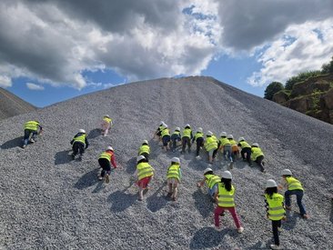 Kinder klettern einen Kiesberg hinauf