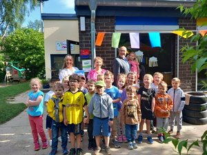 Gemeinschaftsfoto des ehemaligen Bürgermeisters, Erzieherinnen und Kindern am KiTa-Eingang