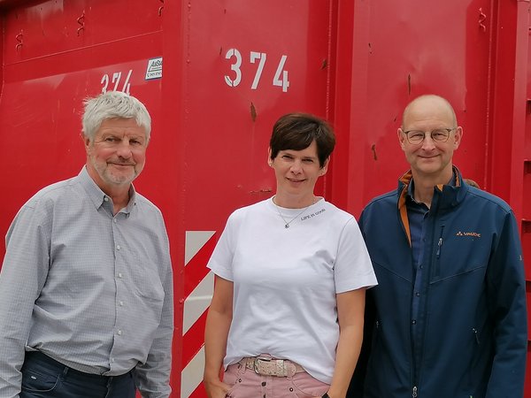 Wirtschaftsförderer mit dem geschäftsführenden Gesellschafter und der Geschäftsführerin vor einem roten Container