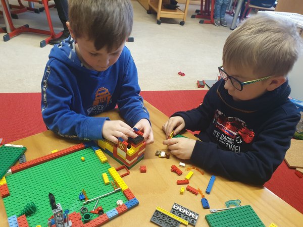 Zwei Kinder bauen mit bunten Legosteinen, Foto: Haus für Kinder