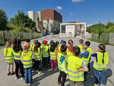 Kinder mit gelben Warnwesten stehen am Eingang des Westkalk-Geländes