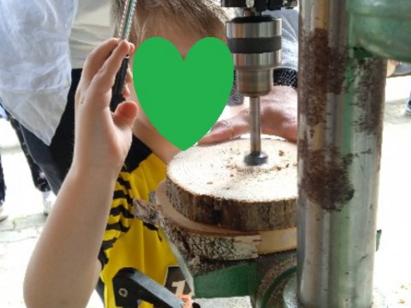 Kind bohrt mit einer Maschine Löcher in eine Baumscheibe, Foto: KiTa Niederbergheim