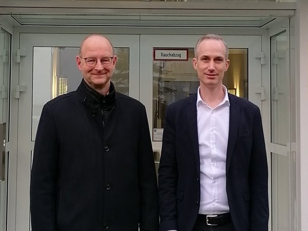 Wirtschaftsförderer und der Geschäftsführer vor dem Gebäude der Infineon Technologies Bipolar