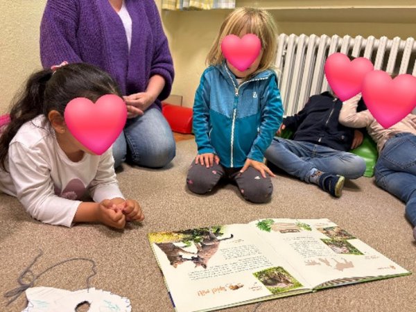 Kinder schauen in ein Bilderbuch zum Thema Wolf