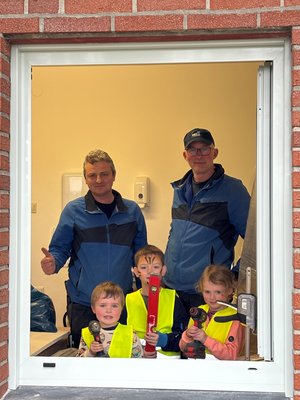 Drei Kinder und 2 Monteure schauen aus einem der neuen Fenster