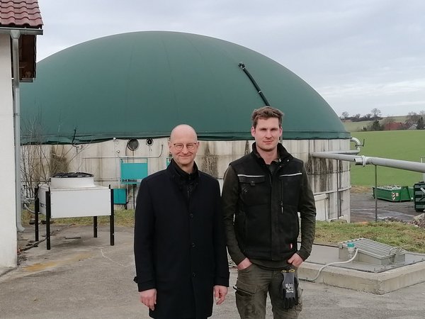 Wirtschaftsförderer und Inhaber vor der Biogasanlage