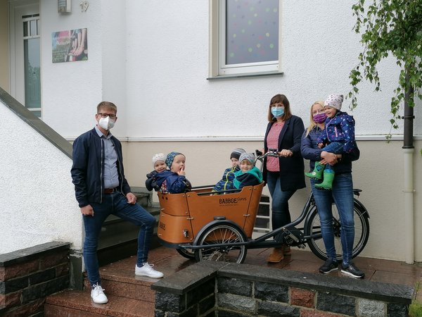 Jugendamtsleiter mit zwei Betreuerinnen und Kindern in Lastenfahrrad