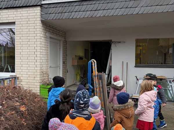 Kinder stehen im KiTa-Eingangsbereich und sehen sich die Fenster an