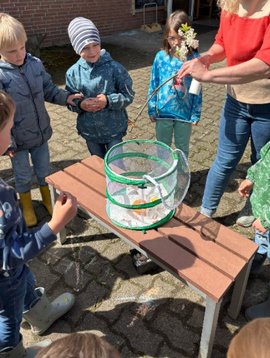 Kinder stehen um eine geöffnete Voliere