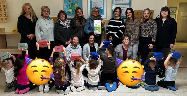 Gruppenfoto der Erzieherinnen und Kinder, die ihre Brotdosen in die Luft halten