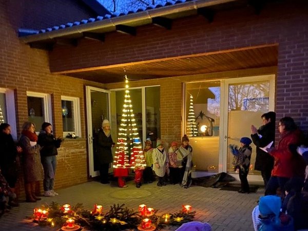 Eltern und Kinder feiern abends im adventlich geschmückten Eingangsbereich