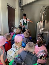 Kinder stehen in Reihe vor dem Bauern, der etwas erklärt